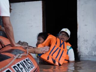 Direktur Utama PLN, Darmawan Prasodjo (kanan) ketika mengevakuasi seorang ibu bernama Murni (54) (kiri) dari banjir yang menggenangi rumahnya di Perumahan Nasional 1 Kayuringin Jaya, Bekasi, Jawa Barat pada Selasa (4/3).