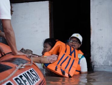 Direktur Utama PLN, Darmawan Prasodjo (kanan) ketika mengevakuasi seorang ibu bernama Murni (54) (kiri) dari banjir yang menggenangi rumahnya di Perumahan Nasional 1 Kayuringin Jaya, Bekasi, Jawa Barat pada Selasa (4/3).